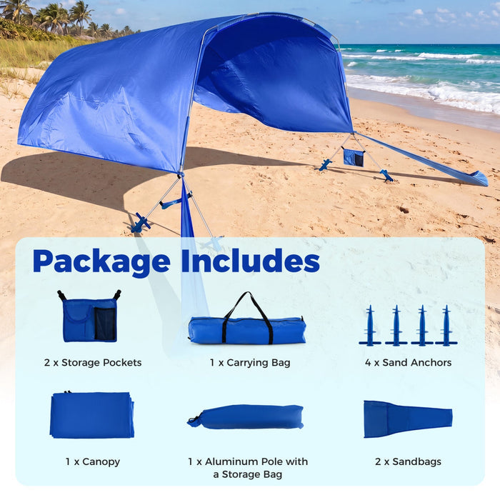 Blue beach canopy set up on a sandy beach with ocean view, including storage pockets, carrying bag, sand anchors, and more.